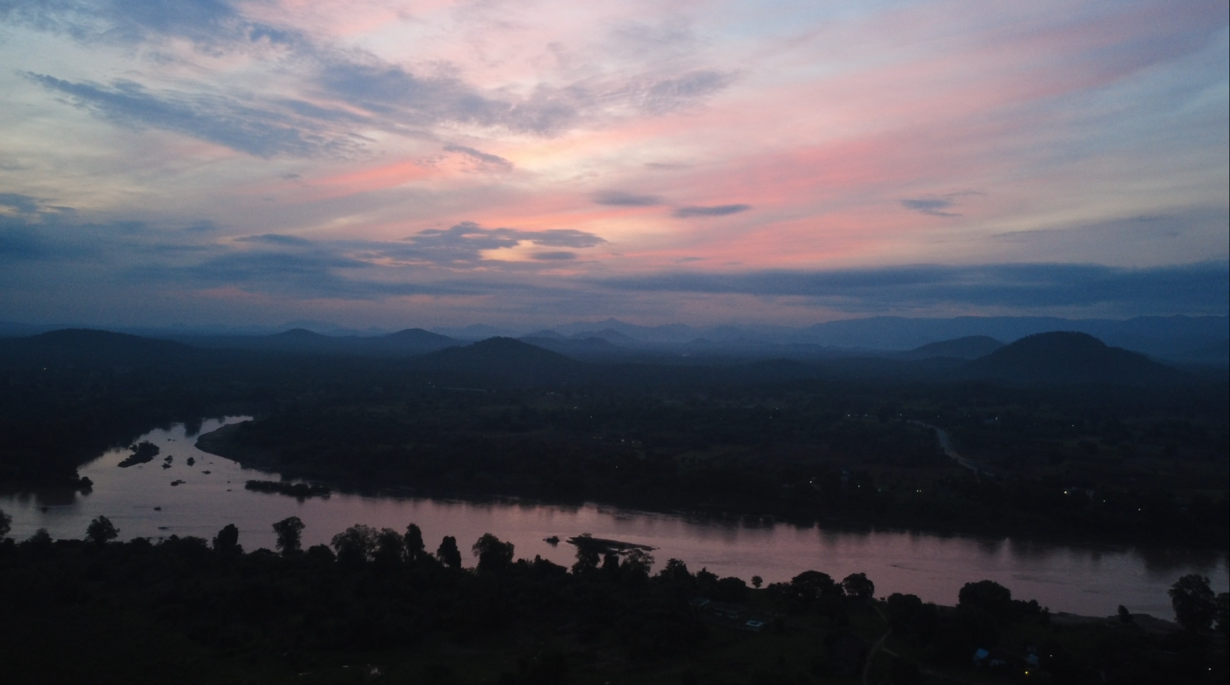 A vibrant pink and orange sunset over a river valley.