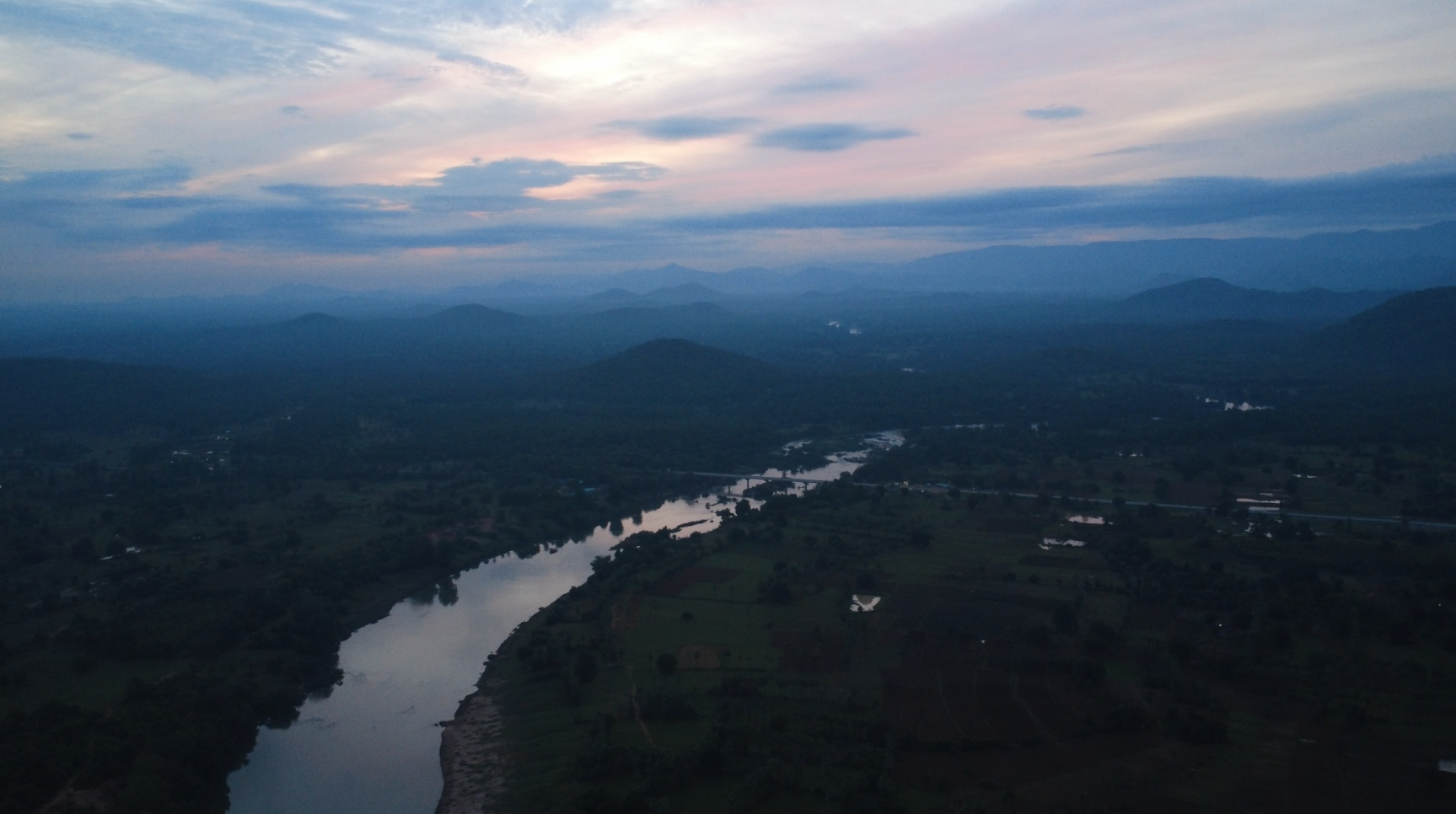 A high-altitude shot of a river winding through a dark, dusky landscape.